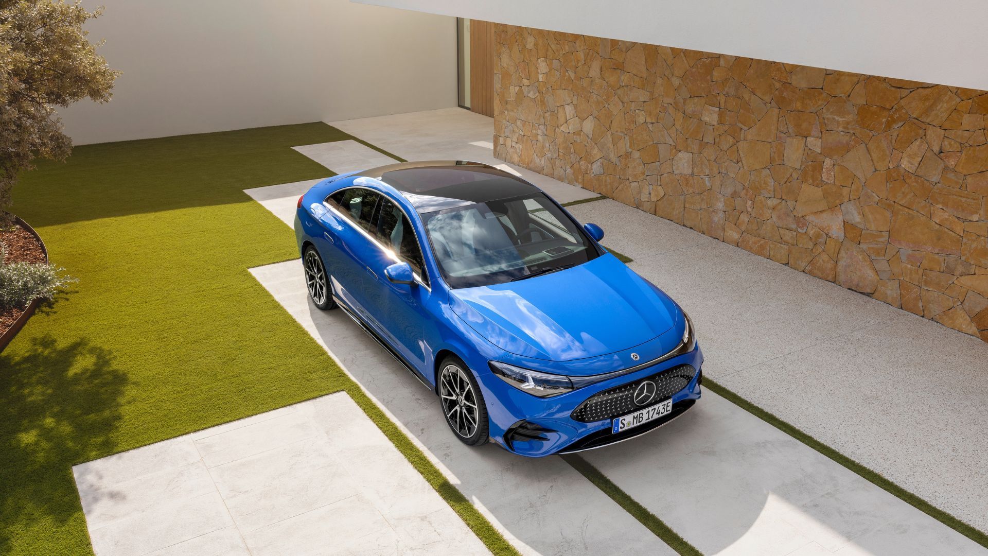 Front three-quarter view of a blue 2026 Mercedes-Benz CLA parked outside of a house.