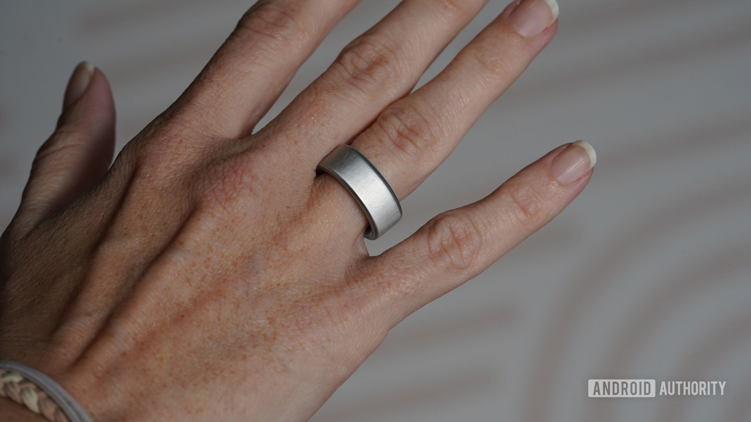 A user models their stilver Oura Ring 4.