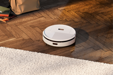 White Roomba 205 robot vacuum cleaning hardwod floor by rug