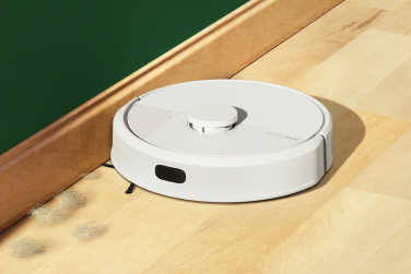 White Roomba 105 robot vacuum cleaning dust bunnies by wall