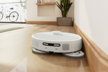 White Roomba Plus 505 robot vacuum mopping hardwood floor near edge of wall